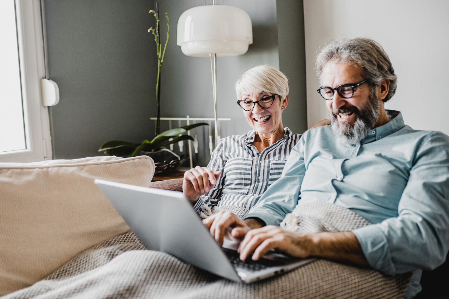 an elderly couple sit on couch 